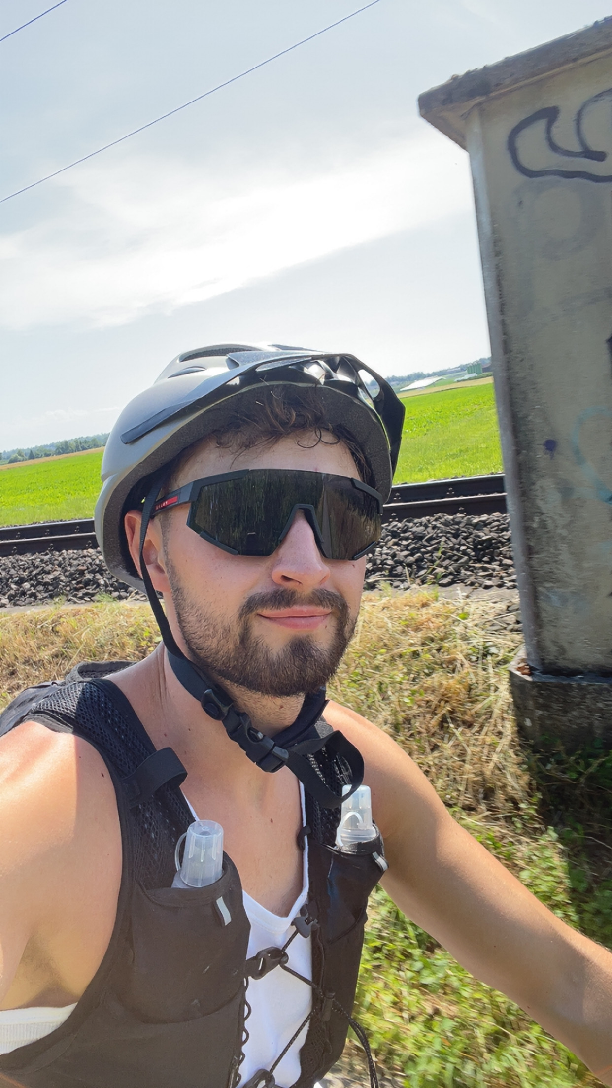 Steven in cycling gear at the start of the tour – helmet, sunglasses and hydration vest on, train tracks visible in background